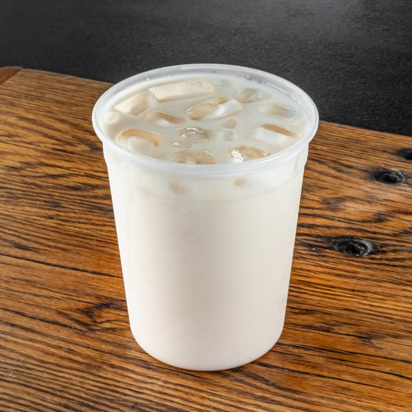 Horchata, a traditional Mexican rice milk drink with ice, in a clear plastic cup.